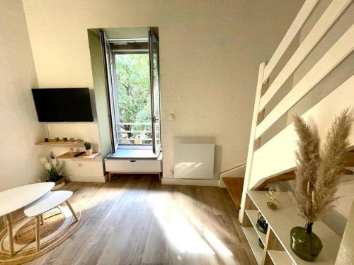 an empty living room with a table and a window at Duplex - A 2 pas des Arènes in Nîmes