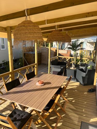 une table et des chaises en bois sur une terrasse dans l'établissement Mobil home climatisé au calme et proche des activités LEGE CAP FERRET, à Lège-Cap-Ferret