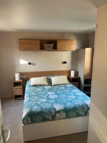 um quarto com uma cama grande e um cobertor azul em Mobil home climatisé au calme et proche des activités LEGE CAP FERRET em Lège-Cap-Ferret