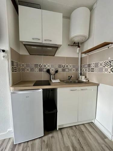 a kitchen with white cabinets and a sink at «Studio 2» rue Huchette - DABNB in Limoges
