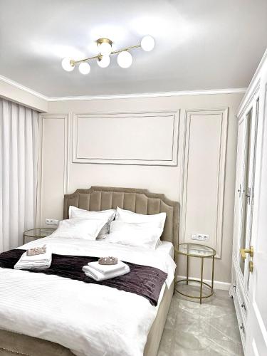 a white bedroom with a large bed with two tables at Luxury RA Apartment in Oradea