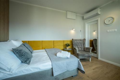a bedroom with a bed and a chair and a clock at WiguryTower Apartaments 98 in Łódź