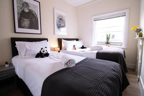 1 dormitorio con 2 camas con un oso panda. en Mayfair Shopping Retreat 2 Bedroom Luxury Apartment 8CB 4th floor without elevator, en Londres