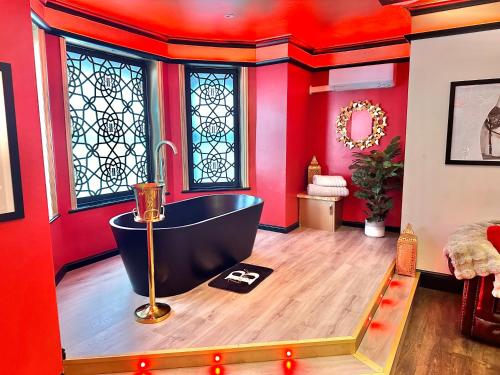 a bathroom with a tub in a room with red walls at Beyond - Romantic Basement Apartment - Close To Beach - With Parking in Bournemouth