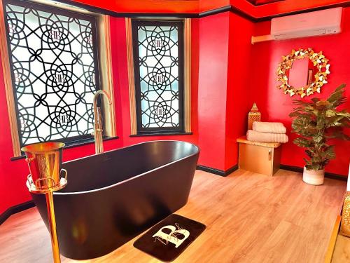 a bathroom with a black tub and red walls at Beyond - Romantic Basement Apartment - Close To Beach - With Parking in Bournemouth