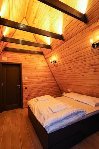 a bedroom with a bed in a wooden room at Tramonto Cabin in Vartop