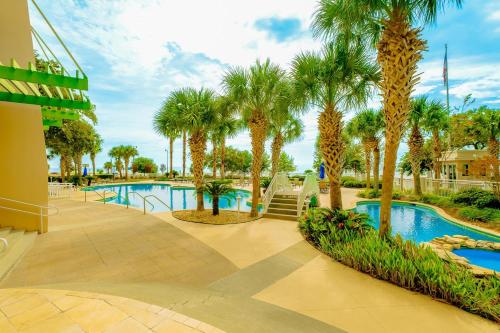 a swimming pool with palm trees in a resort at Legacy I 1008 in Gulfport