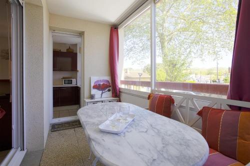 un salon avec une table et une grande fenêtre dans l'établissement Appartement Gabarra et sa loggia - Welkeys, à Capbreton