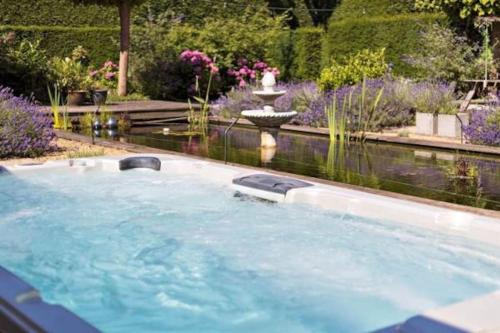 een hot tub in een tuin met een fontein bij SpotElst vakantiehuis in Elst