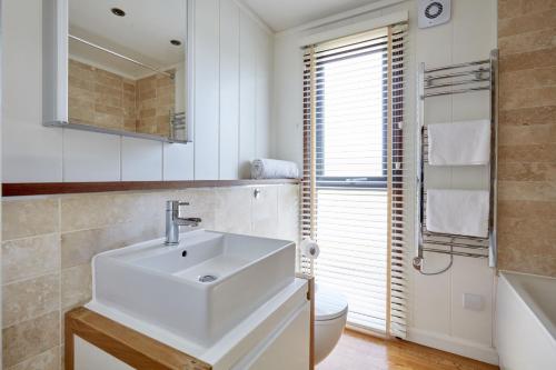 uma casa de banho branca com um lavatório e um WC em Beckington Lodge em Beckington
