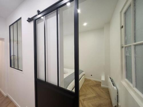 - une porte coulissante en verre dans une pièce avec un miroir dans l'établissement Appartement - Versailles centre, à Versailles