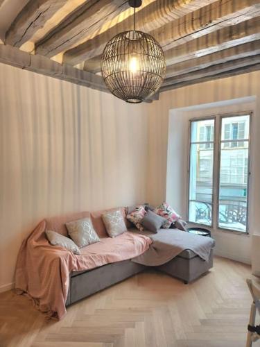 Cette chambre comprend un grand canapé et un lustre. dans l'établissement Appartement - Versailles centre, à Versailles