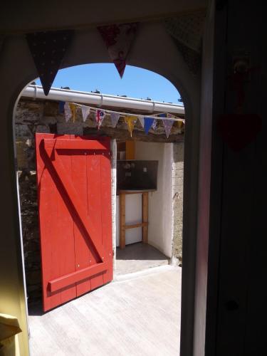 an archway with a red door in a room at Chambre d'hôtes Suite 53m2 ou Caravane vintage avec cuisine et salle de bains privées, B&B 53m2 Suite or Vintage caravan with private kitchen and bathroom in Pleumeur-Gautier