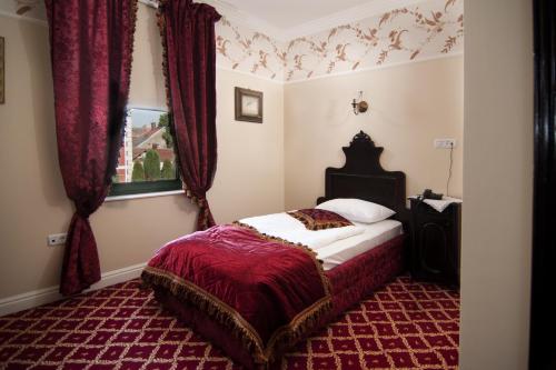 a bedroom with a bed with red curtains and a window at Casa del Sole Boutique Hotel Timisoara in Timişoara