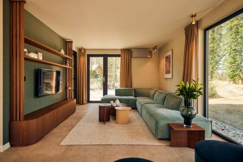 a living room with a green couch and a tv at Dutchen Zeegser Duinen Villalodges in Zeegse