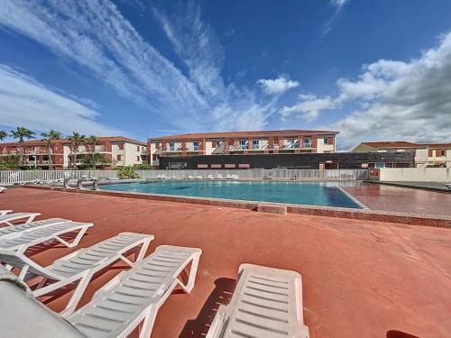 a swimming pool with white lounge chairs and a building at 3284 - appartement 4 couchages avec piscine in Argelès-sur-Mer