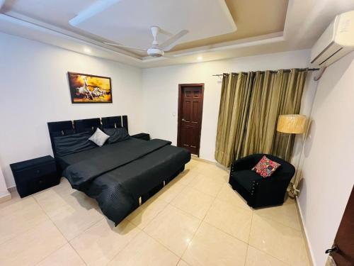 ein Schlafzimmer mit einem schwarzen Bett und einem Stuhl in der Unterkunft Luxe and Family-friendly 2BHK in Islamabad