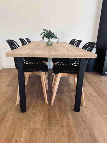une table en bois avec des chaises et un vase avec une plante. dans l'établissement Gîte neuf en ossature bois à 5 minutes de Berck., à Verton