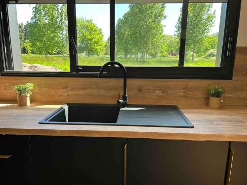- un évier de cuisine avec un robinet à côté d'une fenêtre dans l'établissement Gîte neuf en ossature bois à 5 minutes de Berck., à Verton