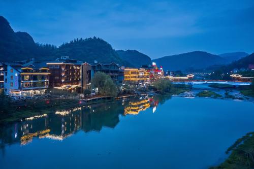 Lee's Boutique Resort في تشانغجياجيه: مدينة بها نهر ومباني في الليل
