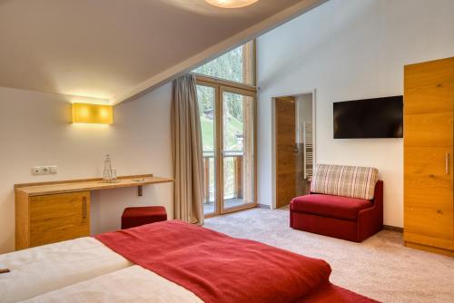 a bedroom with a bed and a desk and a chair at Mallaun Hotel.Erlebnis in See