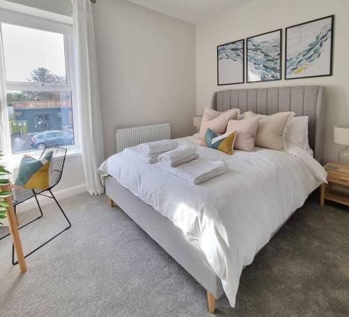 um quarto com uma grande cama branca e uma cadeira em New to 2024 Cosy Beach Home em Castlerock
