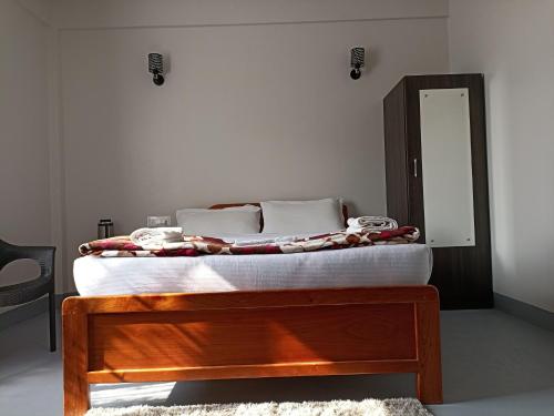 uma cama com uma moldura de madeira e um espelho em HILLSCAPE em Cherrapunji