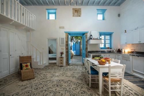 eine Küche mit weißen Schränken sowie einem Tisch und Stühlen in der Unterkunft Mandarin traditional house with outdoor jacuzzi in Koskinou