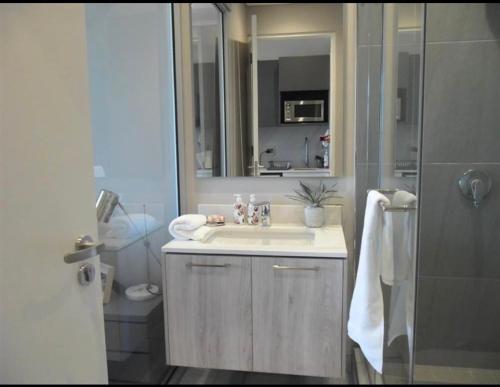 a bathroom with a sink and a mirror and a shower at The Trilogy,Menlyn Maine in Pretoria