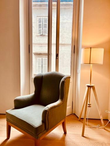 a green chair sitting in front of a window at Zerbion Collection - Palazzina Scotti in Piacenza