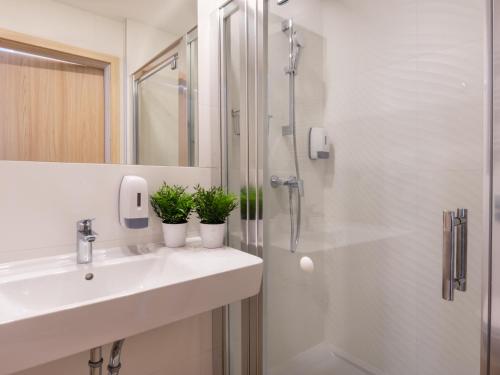 a bathroom with a sink and a shower with two plants at VacationClub Cesarskie Ogrody Apartament 638 in Świnoujście