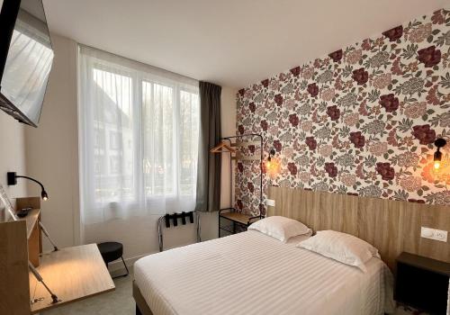 a bedroom with a bed and a floral wall at Hôtel Le Keroman in Lorient