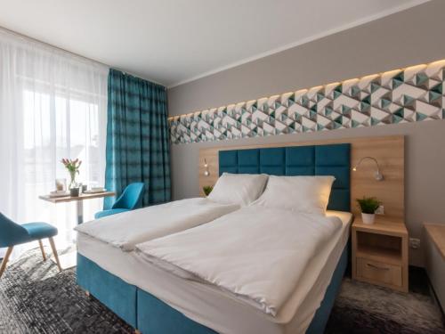 a bedroom with a large bed with a blue headboard at VacationClub Cesarskie Ogrody Apartament 638 in Świnoujście