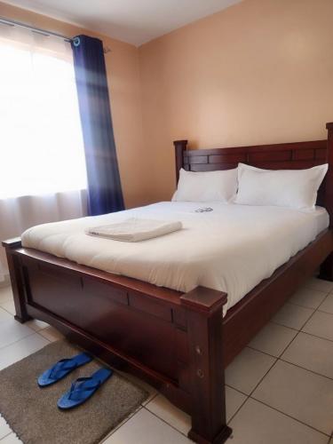 um quarto com uma cama grande com lençóis brancos e uma janela em New Carnation Pangani Hotel em Nairobi