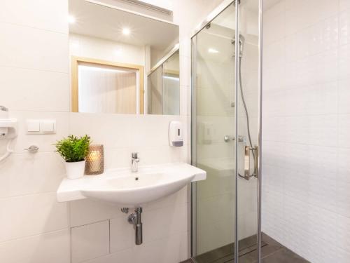a white bathroom with a sink and a shower at VacationClub– Cesarskie Ogrody Apartament 757 in Świnoujście