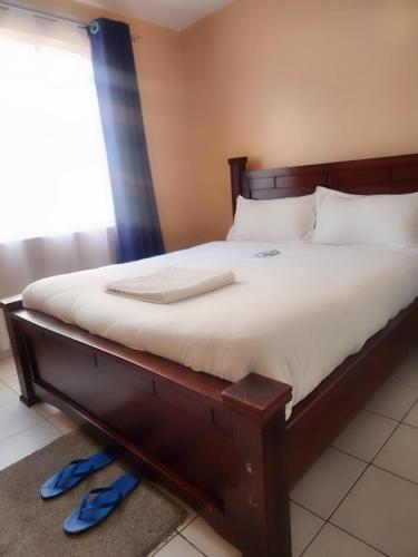 a bed with a wooden frame and white sheets at New Carnation Pangani Hotel in Nairobi