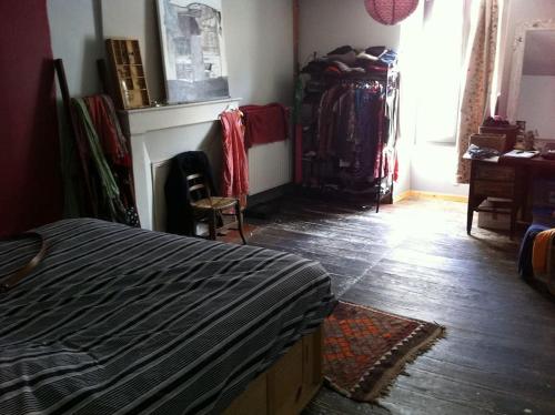 um quarto com uma cama e um armário com roupas em Maison d'artistes jolie et atypique em Vivonne