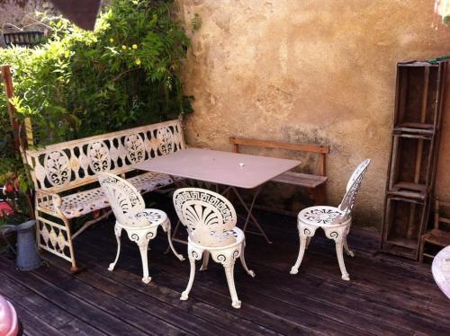une table et des chaises assises sur une terrasse en bois dans l'établissement Maison d'artistes jolie et atypique, à Vivonne