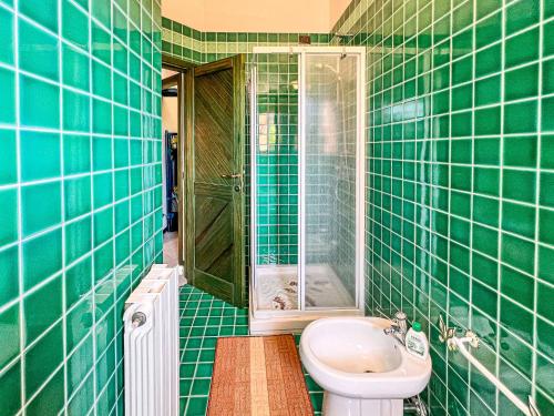 a green tiled bathroom with a toilet and a sink at Cala Reale 101 in Capo Testa