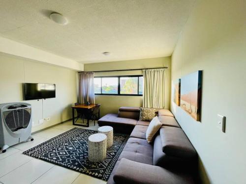 ein Wohnzimmer mit einem Sofa und einem TV in der Unterkunft Cozy Escape in Windhoek