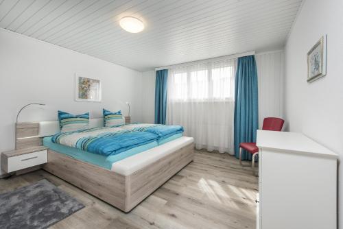 um quarto com uma cama com lençóis azuis e uma janela em Bella Vista em Wildhaus