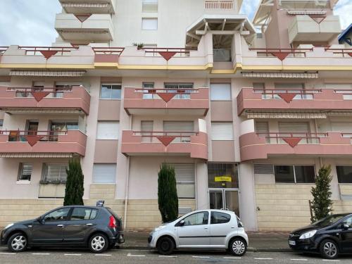 deux voitures garées devant un bâtiment rose dans l'établissement T2 - CENTRE VILLE - PROCHE PLAGE, à Arcachon