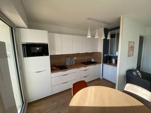 une cuisine avec des armoires blanches et une table dans une pièce dans l'établissement T2 - CENTRE VILLE - PROCHE PLAGE, à Arcachon