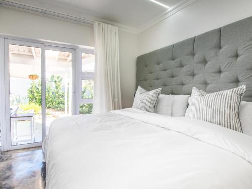 a bedroom with a large white bed and a large window at La Dolce Vita Gordon’s Bay in Gordonʼs Bay