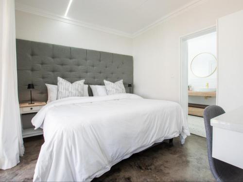 a white bedroom with a large bed with a large headboard at La Dolce Vita Gordon’s Bay in Gordonʼs Bay