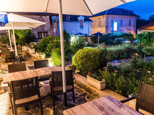 a table and chairs with an umbrella in a garden at Hôtel de France et de Russie in Thiviers