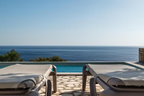 two beds sitting next to a swimming pool with the ocean at Boutique Villa Olivia in Agios Pavlos