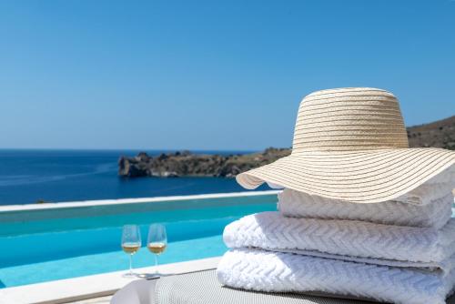 a stack of towels with a hat and two glasses of wine at Boutique Villa Olivia in Agios Pavlos