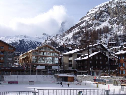 two people skiing in the snow in front of a mountain at Backstage Boutique SPA Hotel in Zermatt