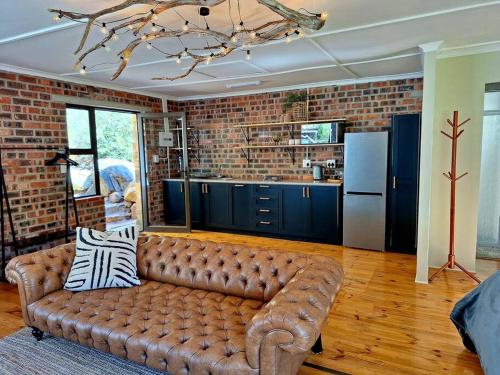 a living room with a brown leather couch in a kitchen at Trout Cottage in Paarl